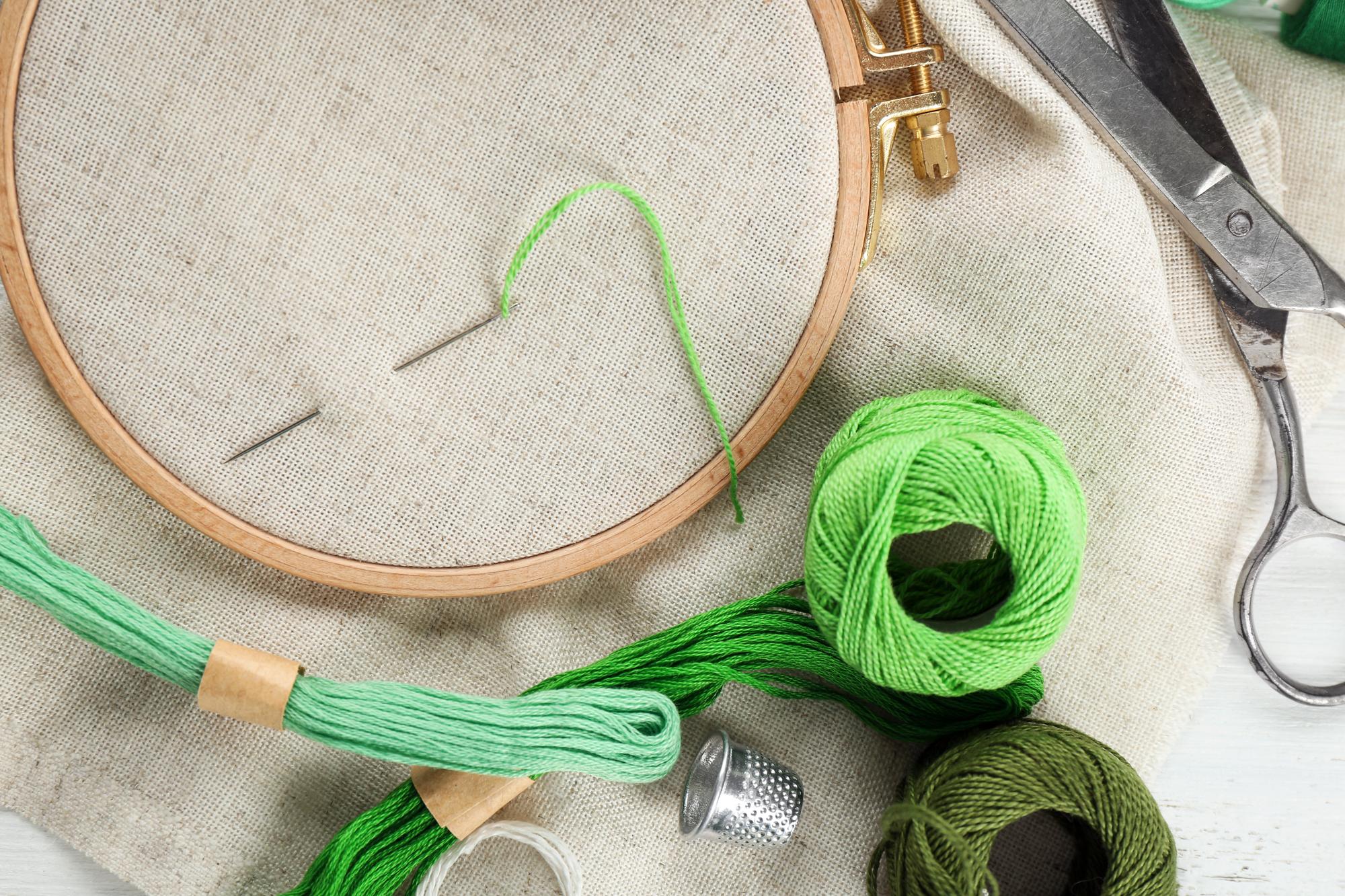 Artisan workspace with needles, threads and an embroidery hoop